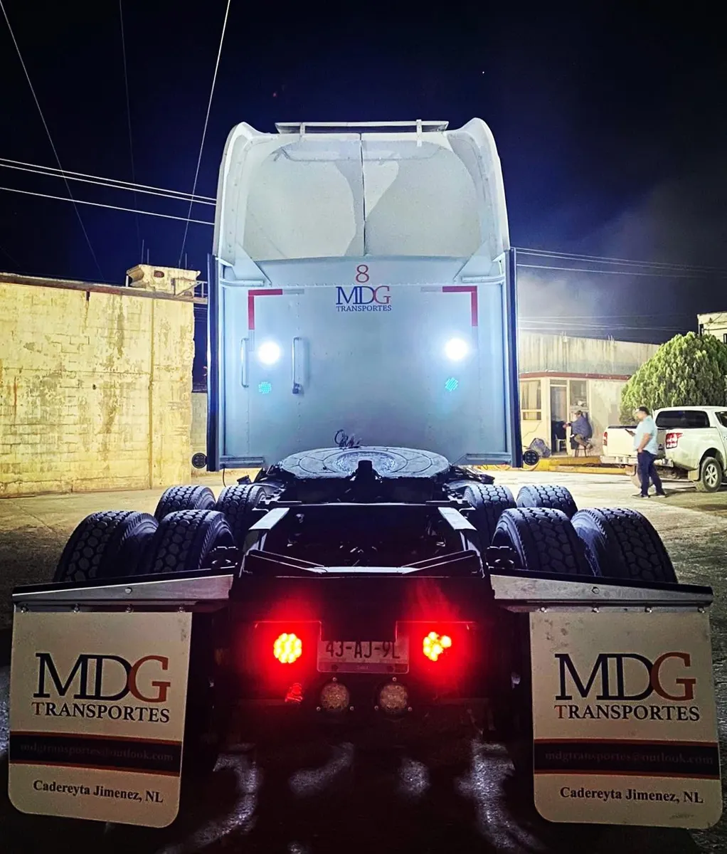 Tractocamión de noche con loderas personalizadas visibles bajo las luces traseras
